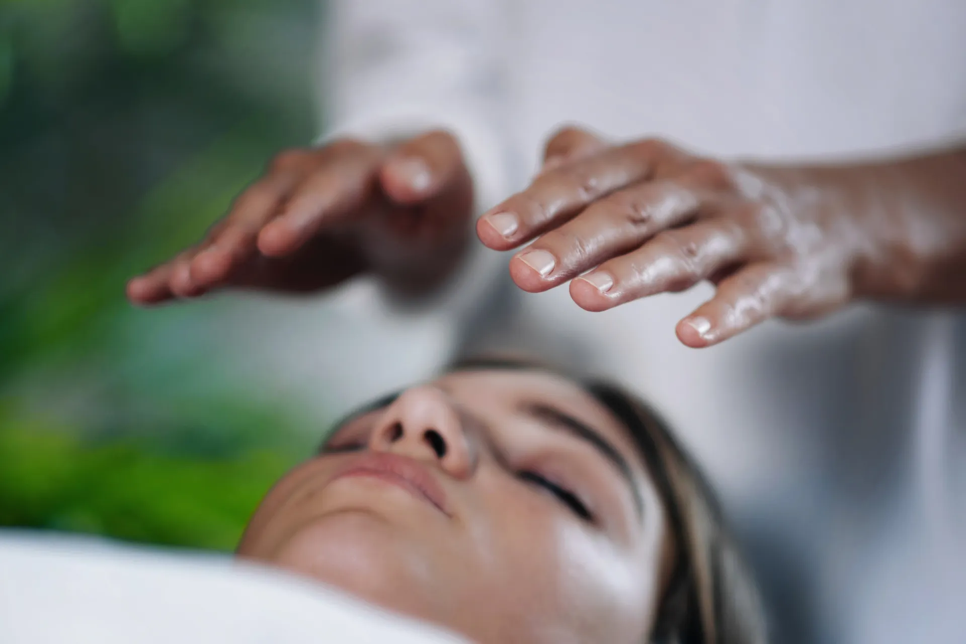 Reiki healing session with hands over client's face.